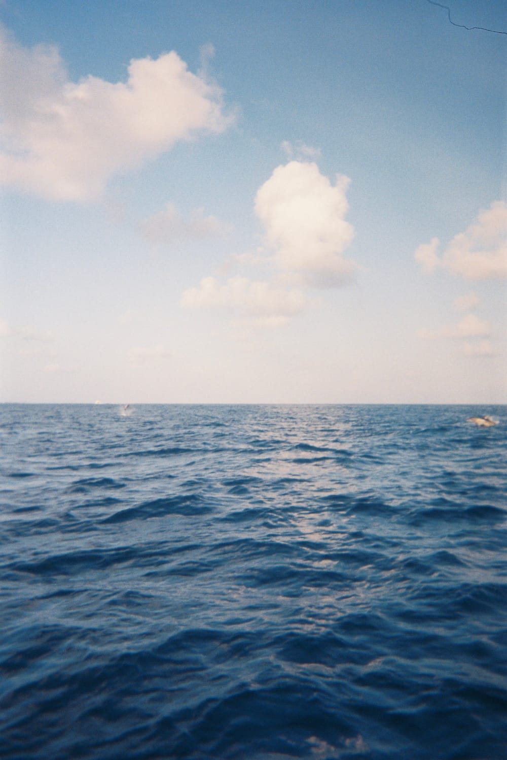 Calm sea meeting the horizon beneath scattered clouds